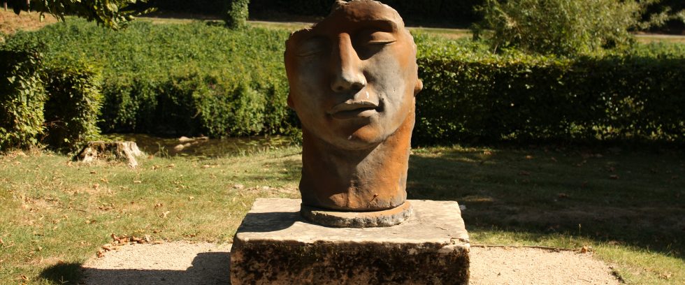 A statue of a face in a garden.